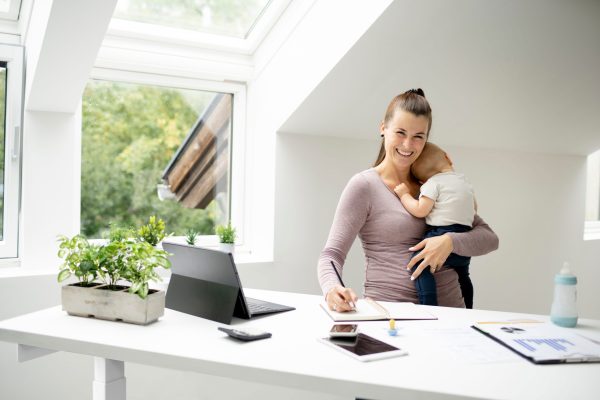 Mutter im Homeoffice am höhenverstellbaren Schreibtisch